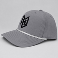 Load image into Gallery viewer, A light gray baseball cap with a black stylized 'MS' logo on the front and a white braided trim along the brim, displayed on a white chair in front of white paneled doors.