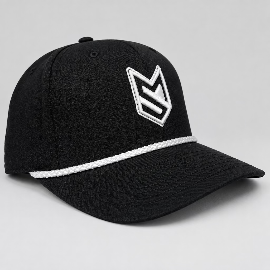 A black baseball cap with a white embroidered geometric logo on the front and a white braided stripe across the brim, resting on a white chair in front of white paneled doors.