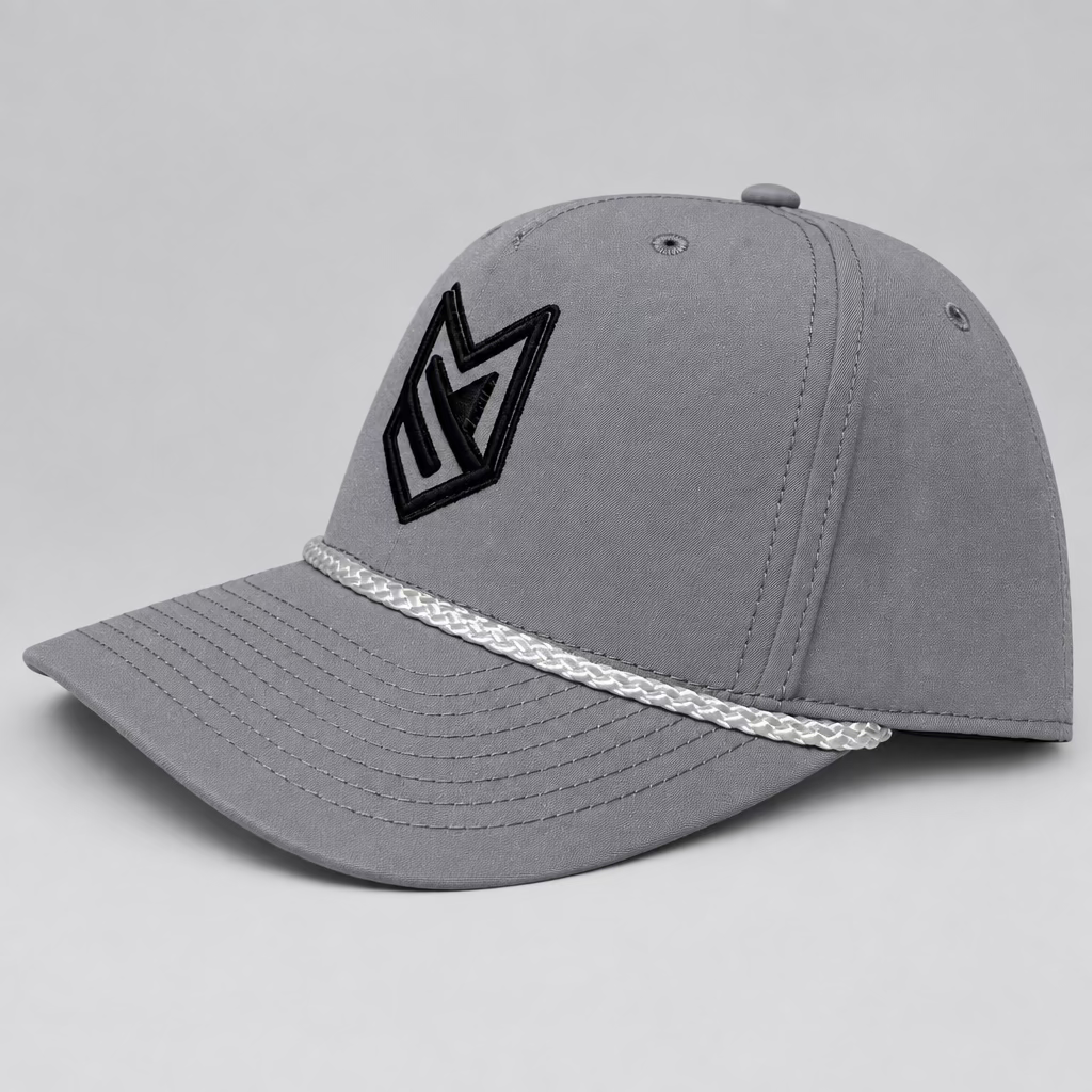A light gray baseball cap with a black stylized 'MS' logo on the front and a white braided trim along the brim, displayed on a white chair in front of white paneled doors.